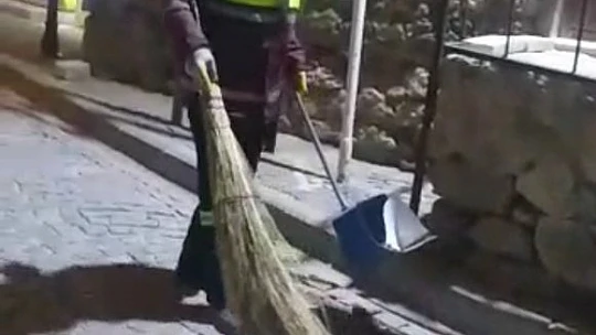 Hem çevreyi temizliyor hem de sokak kedisine süpürgesi ile masaj yapıyor